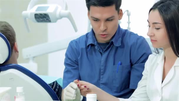 Zahnarztpraktikantin. Der Zahnarzt untersucht die Zähne und zeigt der Praktikantin, wie Siegel zubereitet werden - Filmmaterial, Video