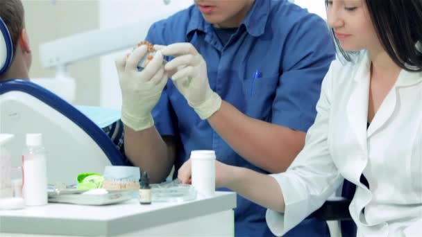 Girl intern with dentists. Dentist beside the girl-intern at the table with dental instrument - Footage, Video