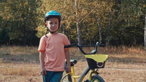 Portret chłopca w kasku rowerowym na spacerze. Dziecko aktywnie odpoczywa podczas jazdy na rowerze. Wysokiej jakości materiał 4k - Materiał filmowy, wideo