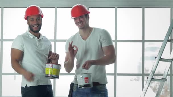 Construcción, reparación y mudanza a un apartamento. Dos trabajadores que usan cascos hacen mediciones de ventanas y reparaciones en una nueva escalera de apartamento mientras están de pie en un apartamento vacío y muestran que están bien
 - Metraje, vídeo