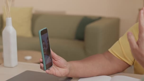 アジアの女性の友人と家に滞在しながら,娘と孫娘とのスマートフォンでビデオチャットを持っている幸せなアフリカ系アメリカ人のシニア女性 - 映像、動画