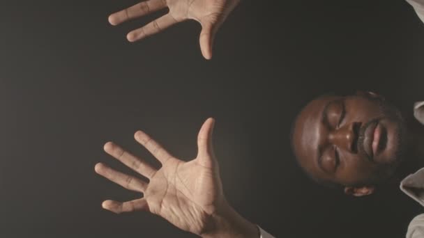 Ritratto verticale dell'uomo afroamericano in piedi con gli occhi chiusi e le palme aperte davanti alla macchina fotografica che assomiglia a Dio o al mago - Filmati, video