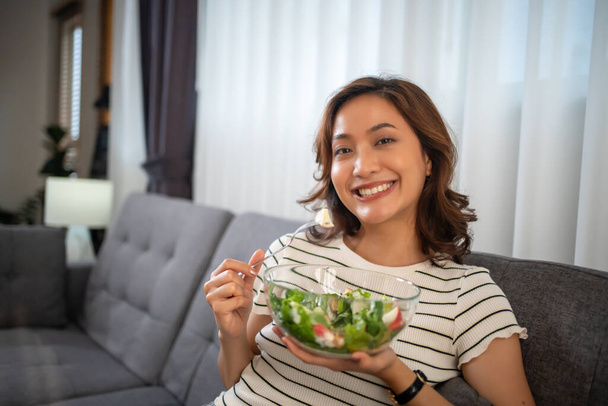 женщина ест здоровый салат на обед во время работы с ноутбуком в домашнем офисе. - Фото, изображение