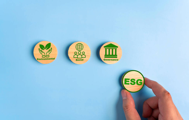 Рука тримає дерев'яні кубики з абревіатурою ESG. ESG концепція екології, соціального та управління. Сталий розвиток корпорацій. - Фото, зображення