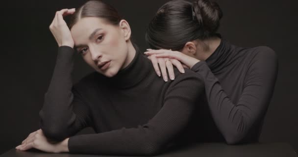 Deux jeunes femmes élégantes avec un bon maquillage sur fond noir. Slow Motion, prise de vue studio. - Séquence, vidéo