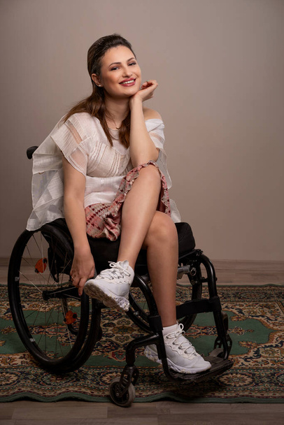 Μια γυναίκα αποπνέει αυτοπεποίθηση και ομορφιά από την αναπηρική καρέκλα της, επιδεικνύοντας το λαμπερό χαμόγελο και το πνεύμα της, αποδεικνύοντας ότι η ομορφιά δεν γνωρίζει σύνορα και προκλήσεις χρησιμεύουν μόνο για να την ενισχύσουν. - Φωτογραφία, εικόνα