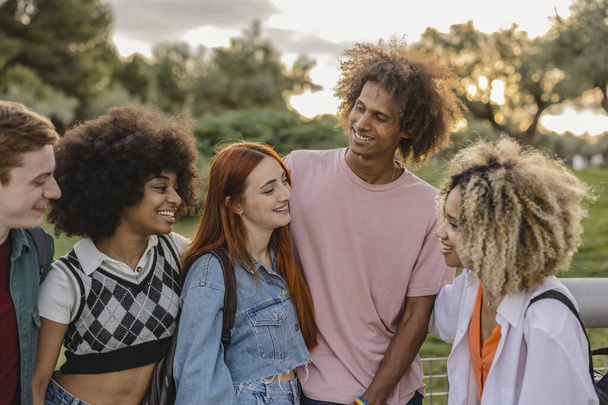 group of multiracial young people chatting outdoors at sunset - Photo, Image