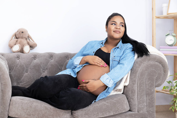 Těhotná Afroameričanka na pokoji na gauči. - Fotografie, Obrázek