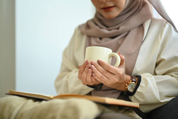 Расслабленная пожилая женщина, сидящая на кресле, пьет горячий чай и отворачивается.. - Фото, изображение
