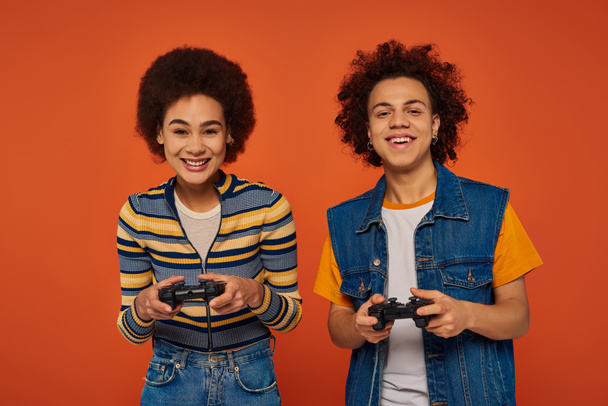 good looking african american brother and sister playing video games with joysticks, family concept - Foto, Imagem