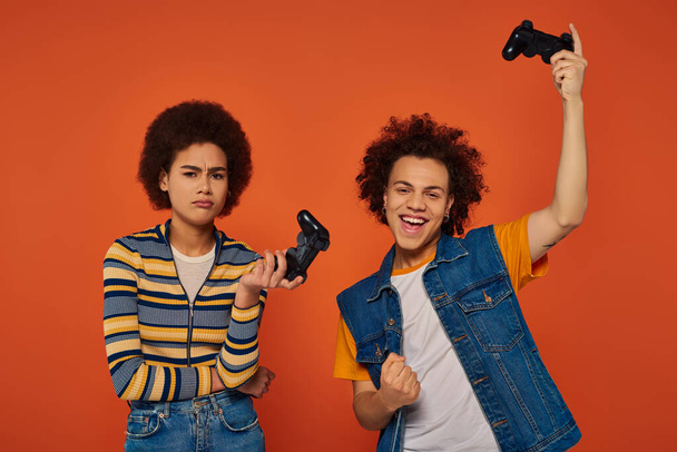 молодые африканские американский брат и сестра играют в видеоигры с джойстиками, семейная концепция - Фото, изображение