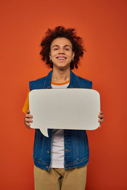 jolly african american male model in casual attire posing with speech bubble on orange backdrop - Photo, Image