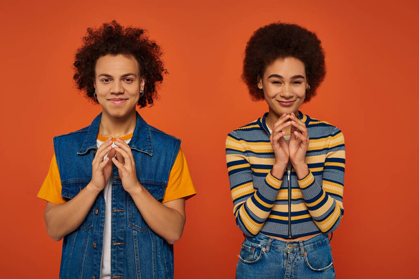 young attractive african american siblings posing together and gesturing lively on orange backdrop - Foto, Imagem