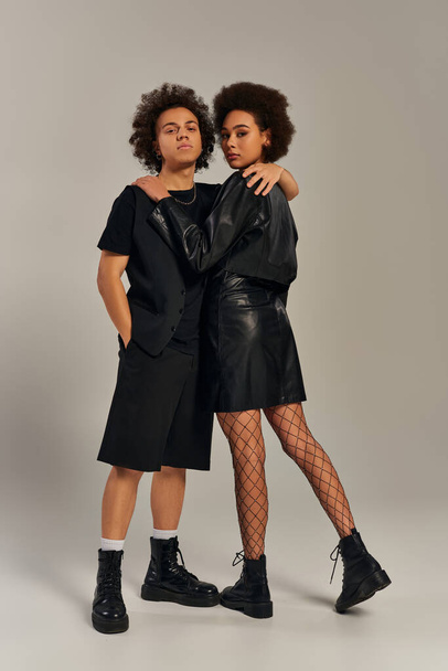 gut aussehende trendige afrikanisch-amerikanische Geschwister in schwarzen Outfits, die sich herzlich umarmen, Familienkonzept - Foto, Bild