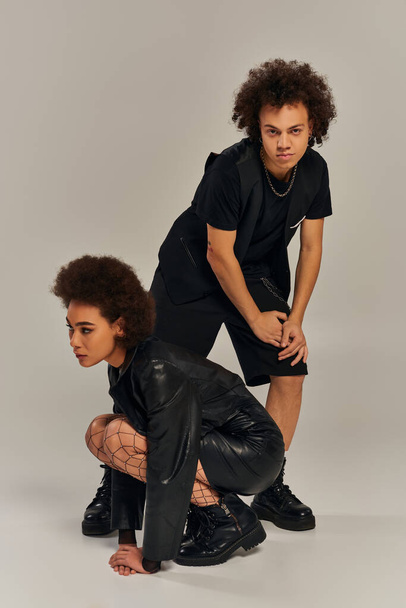 stylish african american brother and sister in vivid black outfit posing together on gray backdrop - Photo, Image