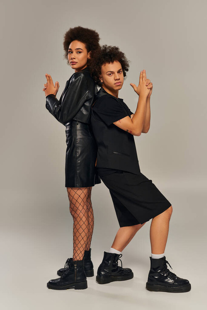 moda afroamericana hermano y hermana en negro trajes posando juntos en gris telón de fondo - Foto, Imagen