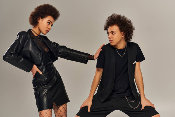 stylish african american brother and sister in trendy black outfit posing together on gray backdrop - Photo, Image