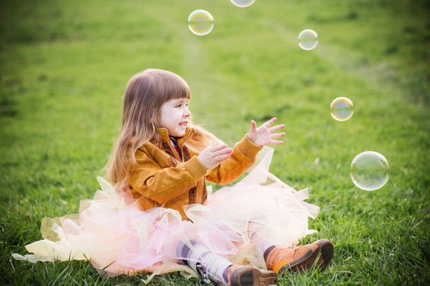 小さな女の子は屋外の泡で遊んでいます。 - 写真・画像