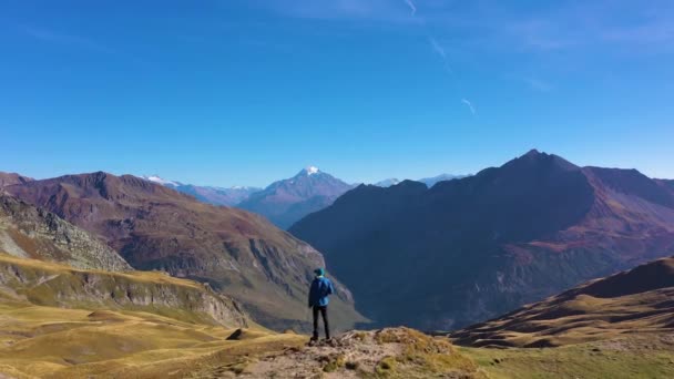 Wandelaar Man in Blue Jacket kijkt naar de bergen. Heuvels en bergen. Kolonel Croix du Bonhomme. Franse Alpen, Frankrijk. Luchtfoto 's. Drone vliegt voorwaarts. - Video