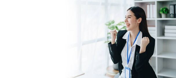Ritratto di una donna imprenditore mostrando un volto felice sorridente come ha investito con successo la sua attività utilizzando i computer e documenti di bilancio finanziario sul lavoro. - Foto, immagini
