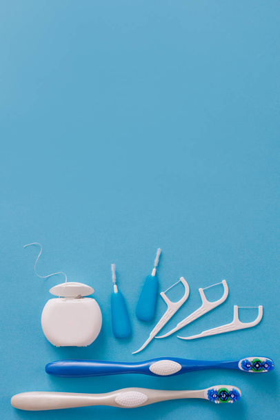 Λευκό οδοντικό νήμα, οδοντογλυφίδες και πινέλα σε μπλε φόντο με copyspace - Φωτογραφία, εικόνα