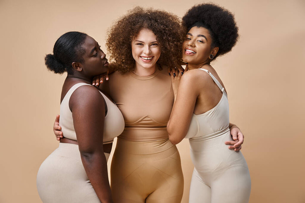 joyeuse femme afro-américaine qui sort la langue presque positive plus les petites amies de taille sur beige - Photo, image