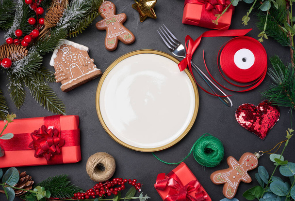 Placa branca redonda vazia com garfo e presentes embrulhados com decoração de Natal em um fundo preto. Fundo festivo - Foto, Imagem