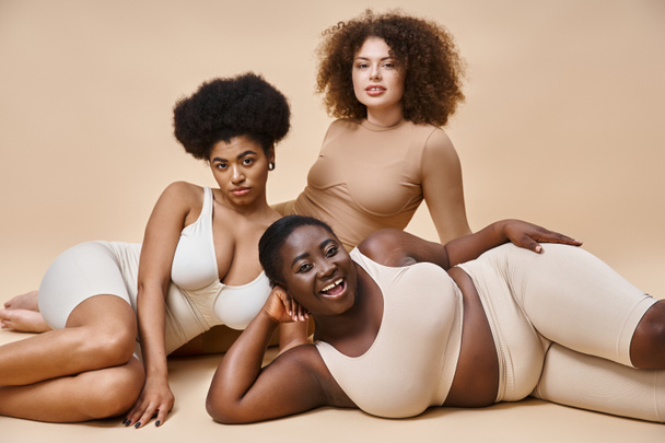 selbstbewusste multirassische Plus-Size-Frauen in Dessous posieren auf beigem Hintergrund, natürliche Schönheit - Foto, Bild
