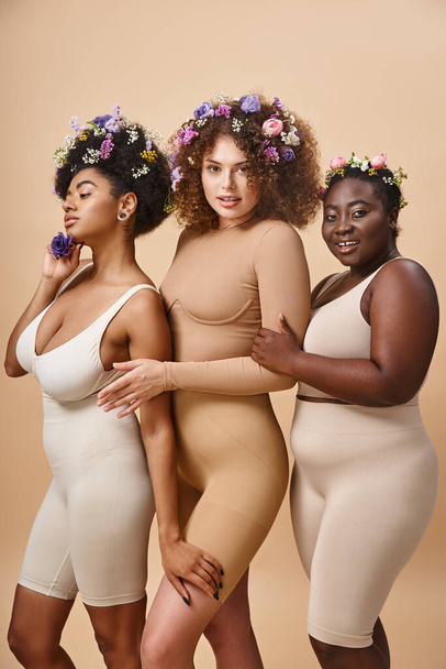 multiétnica más tamaño de las mujeres en lencería con flores de colores en el pelo en color beige, la elegancia con curvas - Foto, imagen
