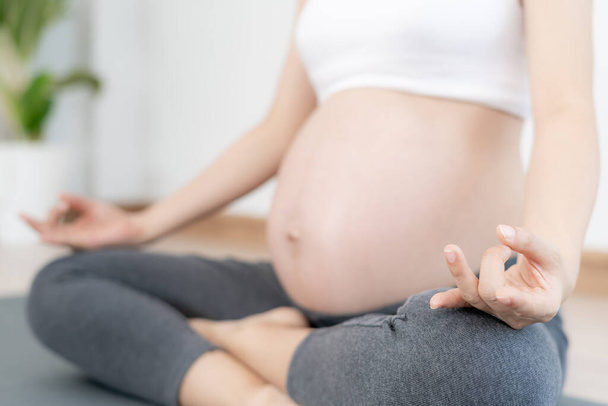 Έγκυος που κάνει γιόγκα σε στρώμα γυμναστικής. διαλογισμό για τη βραχυπρόθεσμη γέννα του διαλογισμού ελκυστική Έγκυος γυναίκα αναψυχή και να χαλαρώσετε, αναπνοή και ηρεμία με γιόγκα. Αυτοφροντίδα - Φωτογραφία, εικόνα