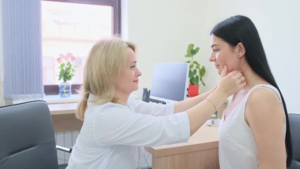 μια γυναίκα γιατρός εξετάζει τους ασθενείς λαιμό στο γραφείο - Πλάνα, βίντεο