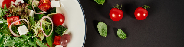 foto vista superior del plato con ensalada griega tradicional cerca de tomates cherry sobre fondo negro, pancarta - Foto, Imagen