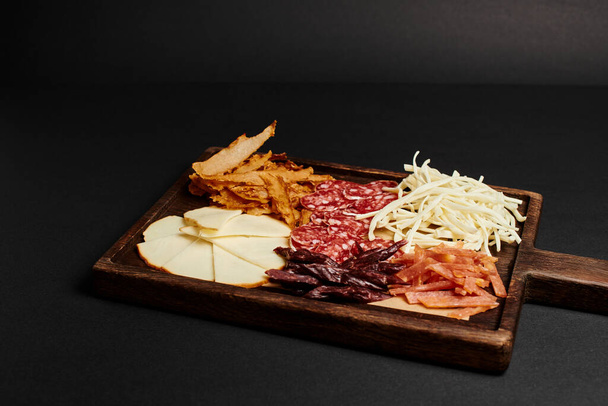 farostlemez sajt válogatással, szárított marhahús és szalámi szeletek fa vágódeszkán - Fotó, kép