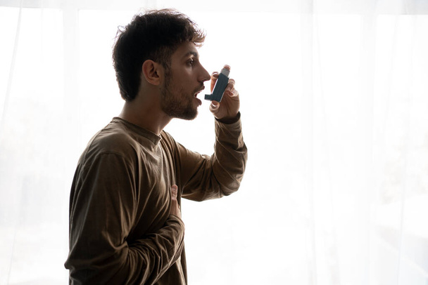 Hindus cierpiący na astmę, młody człowiek mający astmę używając inhalatora do bycia zdrowym. Przestrzeń kopiowania - Zdjęcie, obraz