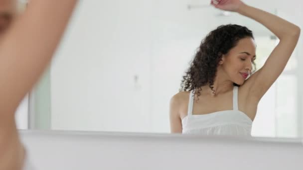 Vrolijke vrouw, huidverzorging en glimlach voor hygiëne, geur of schone oksel kijken in de badkamer spiegel thuis. Vrouwelijke glimlach voor frisse oksels, deodorant of cosmetica voor gezond welzijn met reflectie. - Video