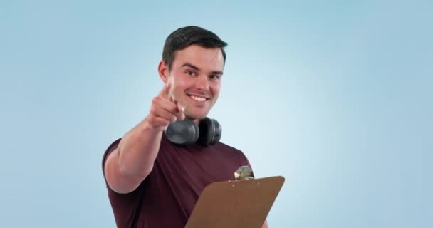 Man, checklist and pointing at you, thumbs up for fitness and sign up to join gym. Portrait, happy coach and clipboard for invitation or registration in studio isolated on a blue background mockup. - Footage, Video