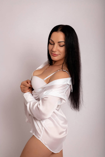 Donna sexy con i capelli lunghi in body su sfondo bianco. Figura sottile, perdita di peso. Foto di alta qualità - Foto, immagini
