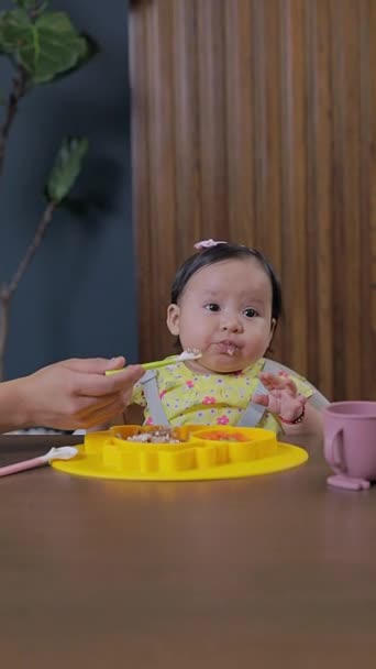 Mutter führt Baby an die ergänzende Fütterung heran und gibt ihm zu Hause feste Nahrung am Esstisch. Konzept der babygeführten Entwöhnung - Filmmaterial, Video