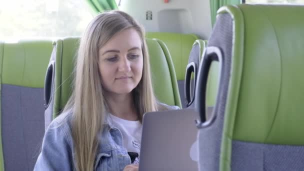 Молода жінка працює на ноутбуці під час подорожі громадським транспортом. - Кадри, відео