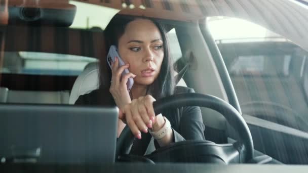 Young businesswoman talking on the mobile phone while driving in the city, looking on the road. Transport, technology, trip, business concept. Slow motion - Footage, Video