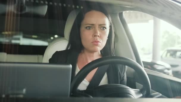 Mujer joven sentada en el coche mientras jura mientras muestra un gesto a un peatón de la ciudad. Conducción de seguridad, transporte, viaje, concepto de negocio. Movimiento lento - Imágenes, Vídeo