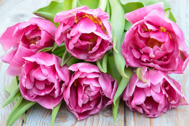 Nahaufnahme eines Bündels rosa lila Tulpen auf gebrauchtem graublau geknüpftem Holz - Foto, Bild