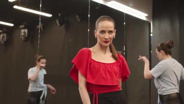 Mittlere Verlangsamung einer jungen attraktiven kaukasischen Frau, die rotes Oberteil und Lippenstift trägt und ausdrucksstarken Flamenco-Tanz in einem geräumigen Gesellschaftssaal mit Ganzkörperspiegeln tanzt - Filmmaterial, Video