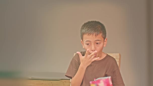 .De jongen zat en at heerlijke popcorn.Boy staren naar mobiele telefoon tijdens het eten van popcorn.. Een jongen zit en eet popcorn en kijkt naar zijn mobiele telefoon. - Video