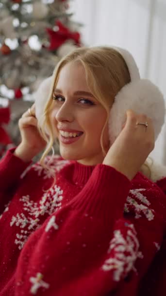 Genç mutlu bir kızın portresi kameraya bakıyor ve parlak Noel çelenkleri yanında gülümsüyor. - Video, Çekim