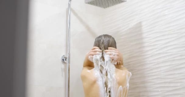 Eine junge Frau wäscht sich die Haare und duscht. Haarpflege. Hübsche junge Frau unter der Dusche und Haarshampoo, Gesundheitskonzept. - Filmmaterial, Video