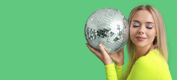 Krásná mladá žena drží disco míč na zeleném pozadí s prostorem pro text - Fotografie, Obrázek