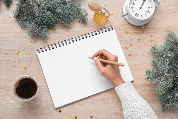 Žena psaní v notebooku s vánoční větve, káva a parfém na světle dřevěném pozadí - Fotografie, Obrázek