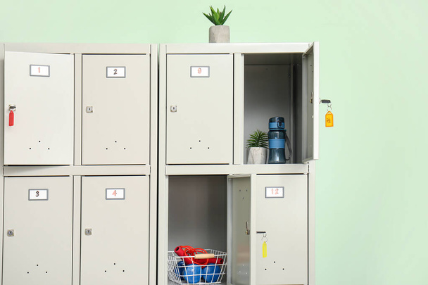 Moderní skříňka se sportovním vybavením a rostlinami v blízkosti zelené stěny - Fotografie, Obrázek
