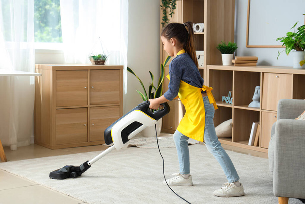 Χαριτωμένο κοριτσάκι σκουπίζει χαλί στο σπίτι - Φωτογραφία, εικόνα